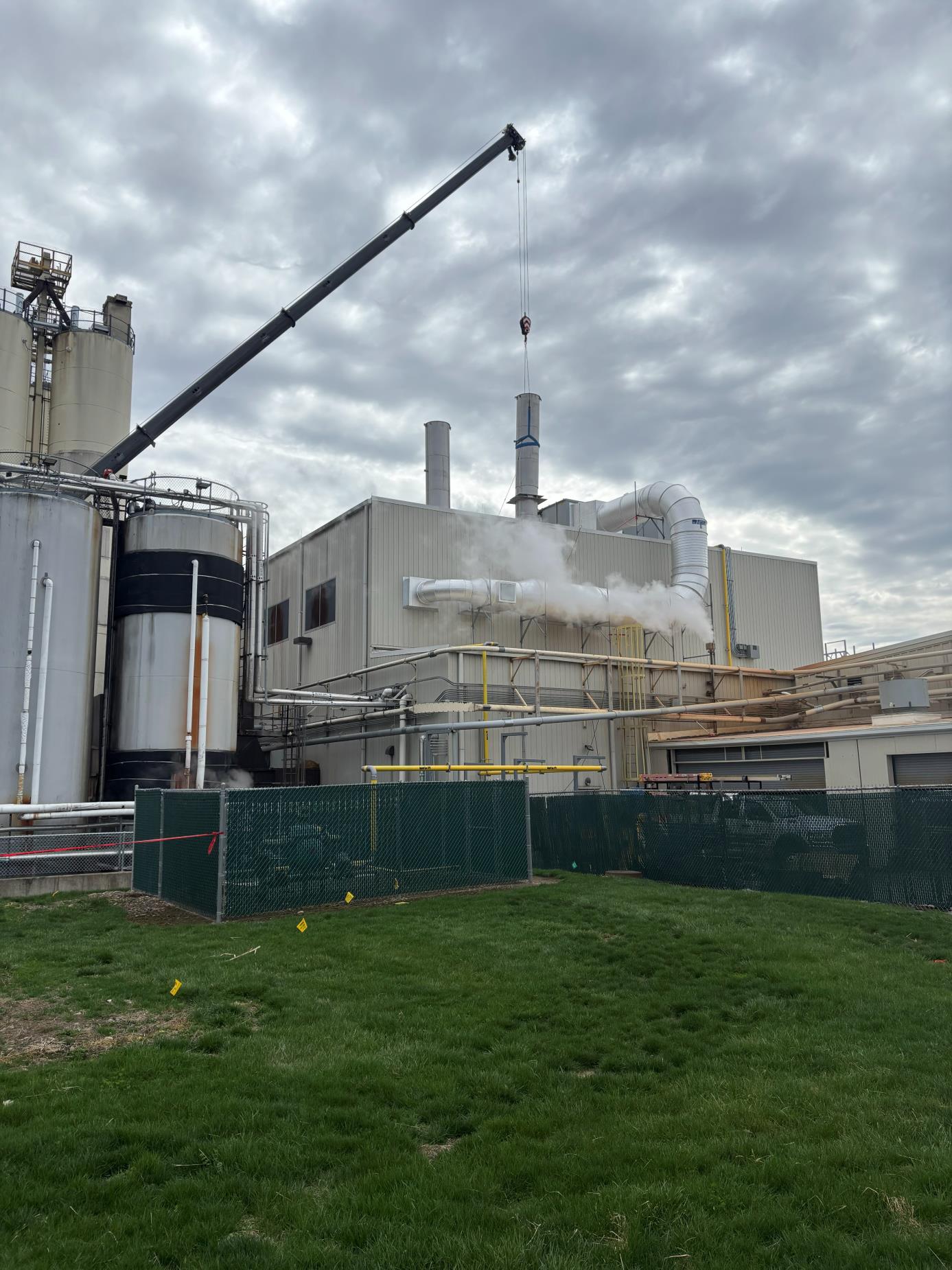 Crane setting a 304 stainless steel roof exhaust stack at a pet food plant